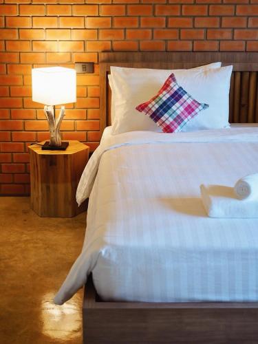 a bedroom with a bed with a lamp and a brick wall at Luck Esan Loft in Ubon Ratchathani