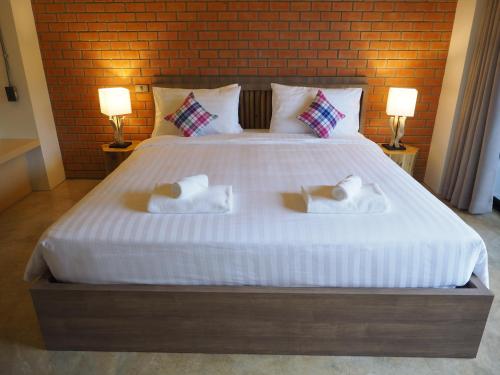 a bedroom with a large white bed with two towels at Luck Esan Loft in Ubon Ratchathani