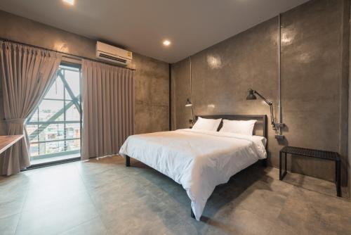 a bedroom with a large bed and a large window at Bed & Bike Hostel in Chiang Rai