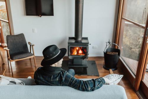 a man sitting on a couch in front of a stove at Kangaroo Ridge Retreat in Healesville