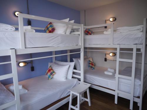 a room with three bunk beds with a stool at Luck Esan Loft in Ubon Ratchathani