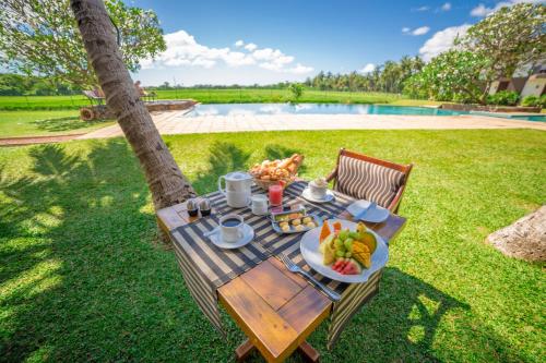 a picnic table with a plate of food next to a tree at Kithala Resort - Thema Collection in Tissamaharama