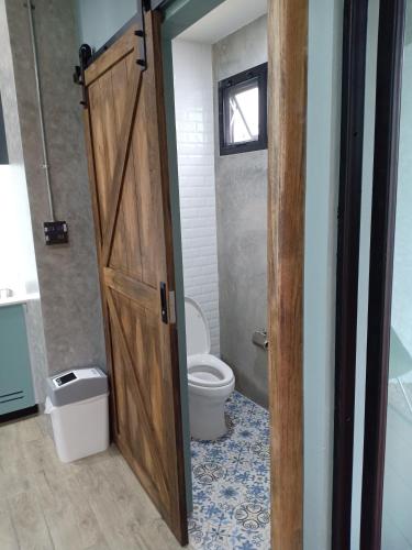 a bathroom with a toilet and a wooden door at Luck Esan Loft in Ubon Ratchathani