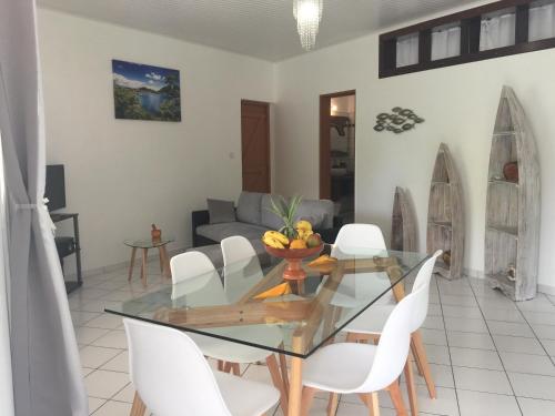 a dining room with a glass table and white chairs at Ô Fil de l'Eau in Pointe-Noire