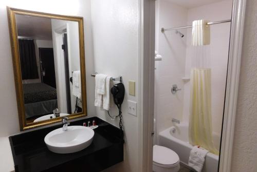 a bathroom with a sink and a toilet and a mirror at Days Inn by Wyndham Oklahoma City NW Expressway in Warr Acres
