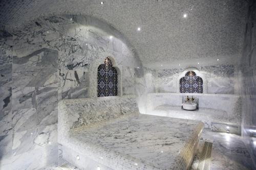a white bathroom with a tub and two windows at Kainar Hotel in Shymkent