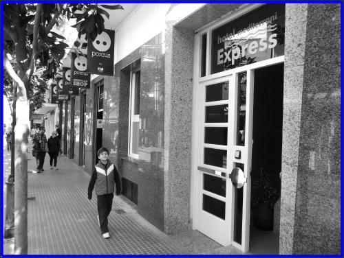 a woman walking down a sidewalk in front of a store at Hotel Mediterrani Express in Calella