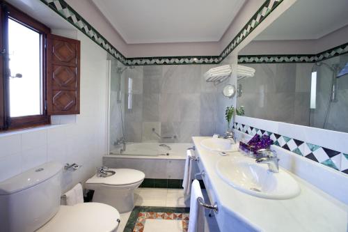 a bathroom with two sinks and a toilet and a tub at Parador de Guadalupe in Guadalupe