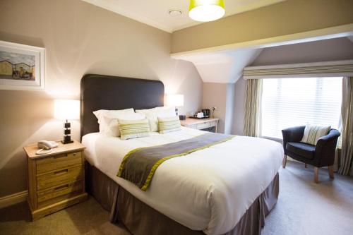 a bedroom with a large bed and a chair at Breckland Lodge in Attleborough