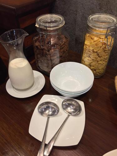 a wooden table with two spoons and jars of milk at Hotel Veneto De Vigan in Vigan