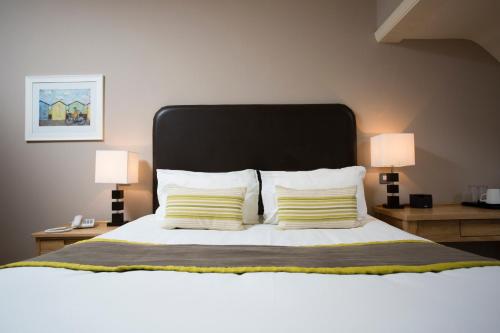 a bedroom with a large bed with two lamps at Breckland Lodge in Attleborough