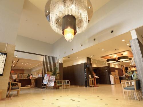 a large lobby with a chandelier and tables and chairs at APA Hotel Sagaeki Minamiguchi in Saga