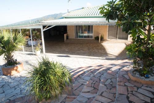 a house with a patio with plants in front of it at La Résidence des Caféiers - Le Tampon in Le Tampon