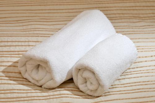 a white towel laying on top of a bed at light hotel & hub in Kyiv