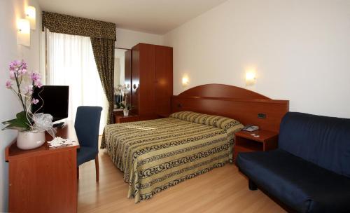 a bedroom with a bed and a blue couch at Hotel Santiago in Lido di Jesolo