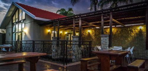 a restaurant with tables and chairs on a balcony at Machauka Lodge in Lephalale