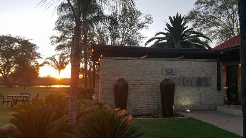 a brick building with a sunset in the background at Machauka Lodge in Lephalale