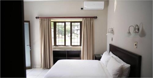 a bedroom with a bed and a window at Machauka Lodge in Lephalale