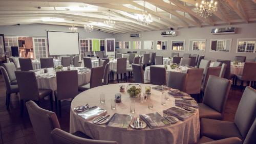 a conference room with tables and chairs and a screen at Machauka Lodge in Lephalale