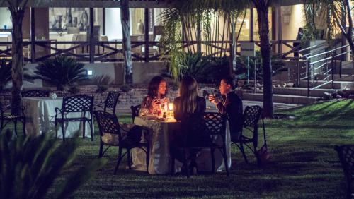 two people sitting at a table in a garden at Machauka Lodge in Lephalale