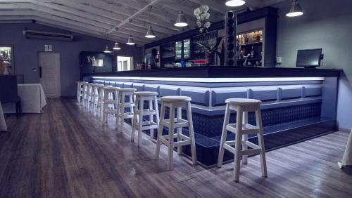 a bar with a row of stools in a room at Machauka Lodge in Lephalale