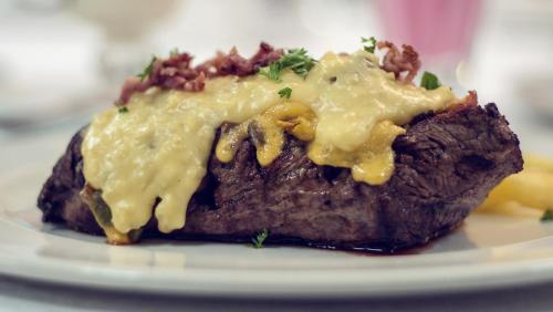a piece of meat with cheese on a plate at Machauka Lodge in Lephalale