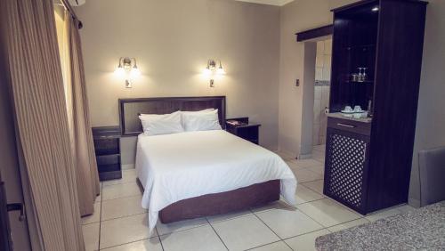 a bedroom with a large bed with white sheets at Machauka Lodge in Lephalale
