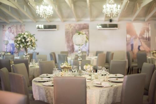 a dining room with tables and chairs and chandeliers at Machauka Lodge in Lephalale
