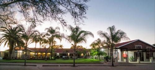 a building with palm trees in front of it at Machauka Lodge in Lephalale