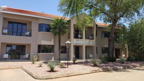 a building with palm trees in front of it at Machauka Lodge in Lephalale