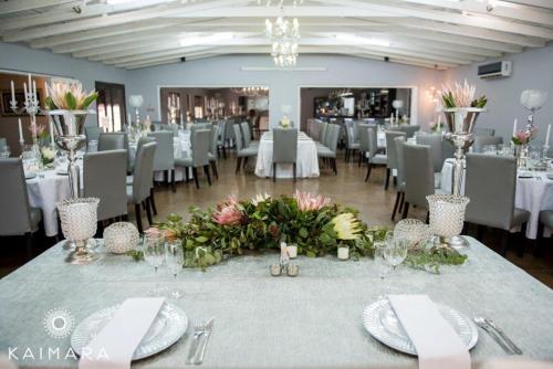 a banquet hall with white tables and chairs and flowers at Machauka Lodge in Lephalale