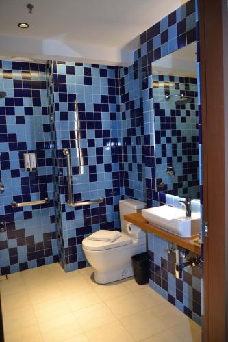 a blue tiled bathroom with a toilet and a sink at Lagùn Hotel in El Nido