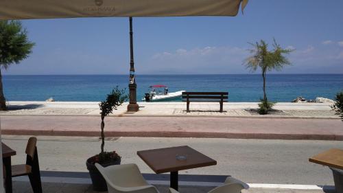 a table and chairs and an umbrella near the ocean at Hotel Kyani Akti in Xylokastron