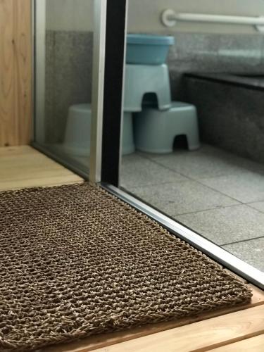 a bathroom with a glass door and a toilet at Fureai No Yado Yasuragi in Nozawa Onsen