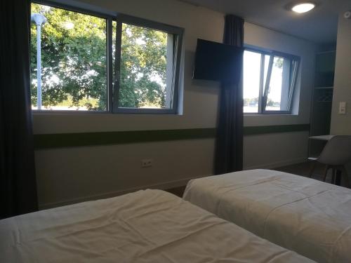 two beds in a room with two windows at Atao Residence- Rennes Sud in Vern-sur-Seiche