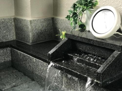 a mirror sitting on top of a stone bath tub at Fureai No Yado Yasuragi in Nozawa Onsen