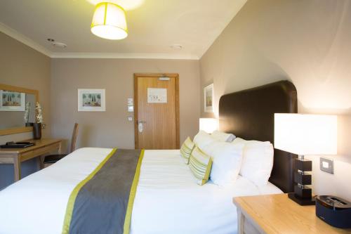 a bedroom with a large bed with white sheets and pillows at Breckland Lodge in Attleborough