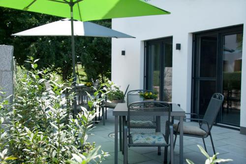 a patio with tables and chairs with an umbrella at Hotel Am Moosrain Garni in Eitting