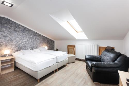 a bedroom with a bed and a black leather chair at Penzion Pohoda in Trutnov