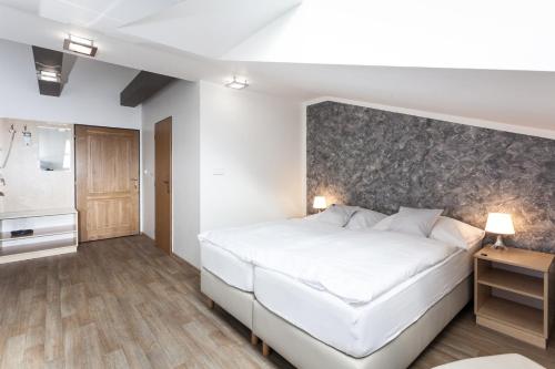 a bedroom with a white bed and a wall at Penzion Pohoda in Trutnov