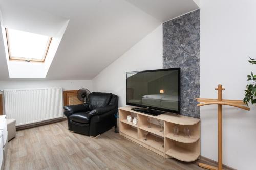 a living room with a tv and a black leather chair at Penzion Pohoda in Trutnov