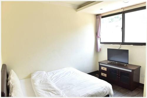 Schlafzimmer mit einem Bett und einem Flachbild-TV in der Unterkunft Lian-Yuan Homestay No. 1 in Insel Nangan