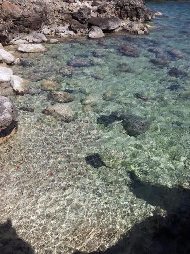 a pool of crystal clear water with rocks and gravel at Villa Vera in Fontane Bianche