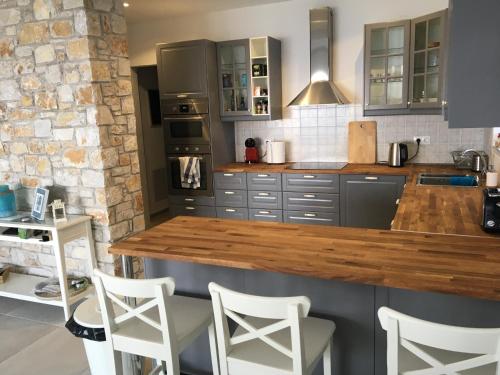a kitchen with a wooden counter top and white chairs at Villa Salina Luxury Pool Villa in Kechria