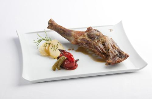 a white plate with a piece of meat and vegetables at Parador de Guadalupe in Guadalupe