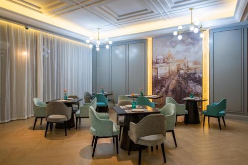 a dining room with tables and chairs and a painting at Mercure Shanghai Jiuting in Shang-hai