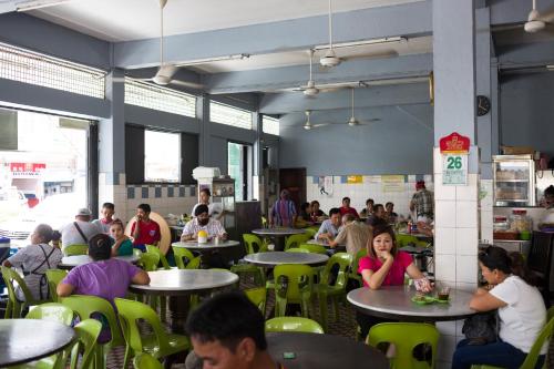 a group of people sitting at tables in a restaurant at Hin Loi Guesthouse in Kota Kinabalu