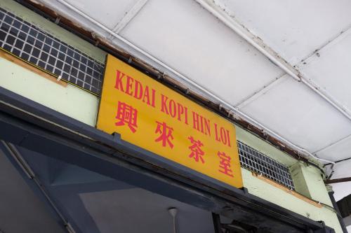 a yellow sign on the side of a building at Hin Loi Guesthouse in Kota Kinabalu