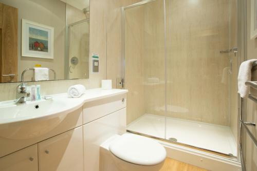 a bathroom with a shower and a toilet and a sink at Breckland Lodge in Attleborough