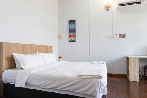 1 dormitorio con 1 cama grande con sábanas blancas en Hin Loi Guesthouse en Kota Kinabalu
